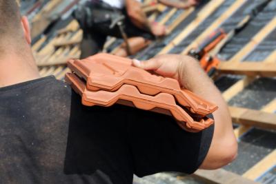 Dachdecker - Geschulterte Pfannen auf dem Dach Dachdecker - Geschulterte Pfannen auf dem Dach